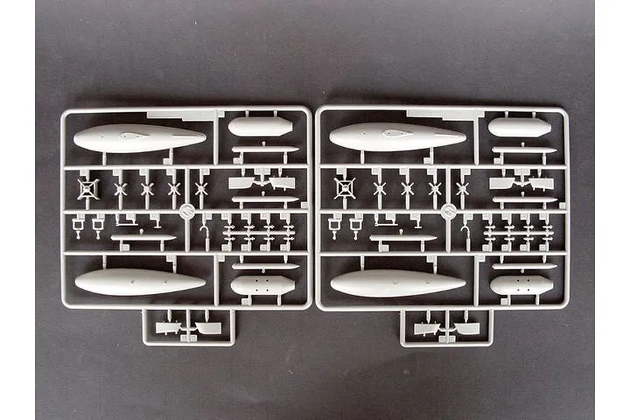 Two identical grey plastic model kit sprues containing aircraft parts like fuel tanks and small components on a dark background.