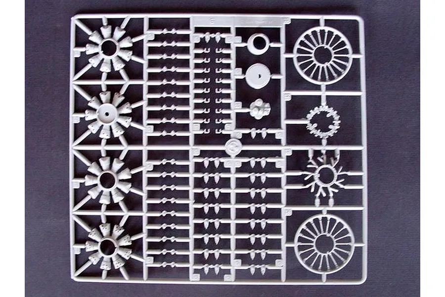 A grey plastic sprue from a model kit containing various engine parts and circular components.