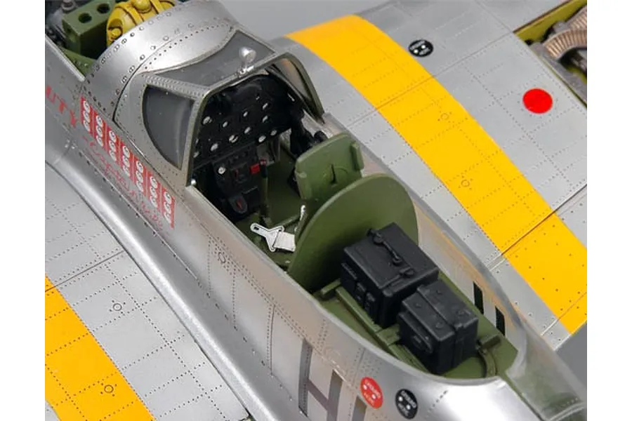 Close-up of the detailed cockpit and fuselage of a 1/32 scale P-51D Mustang plastic model aircraft, showing silver paint, yellow wing stripes, and interior details.