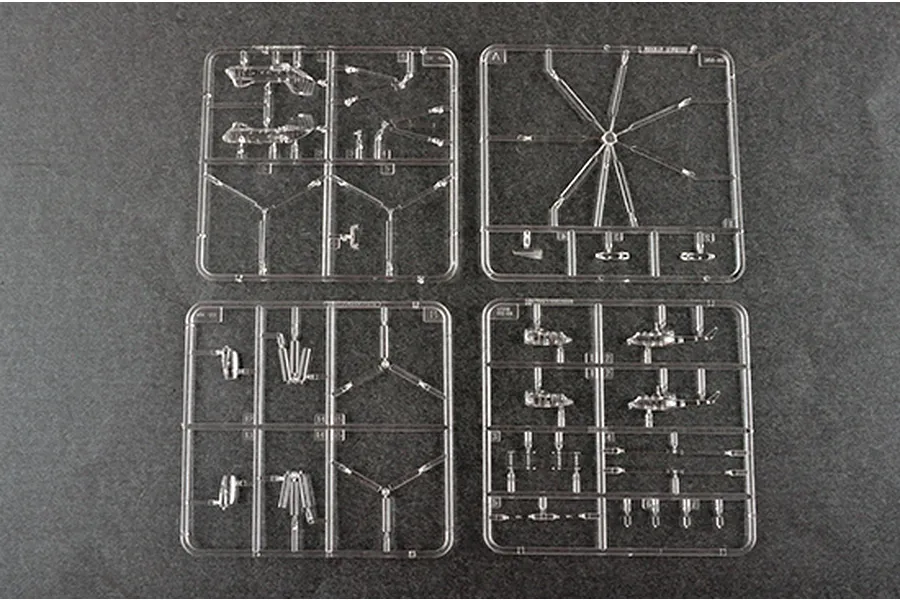 Four clear plastic model kit sprues containing small aircraft and helicopter parts on a dark grey surface.