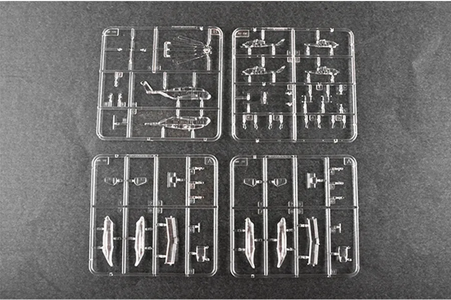 Four clear plastic model kit sprues containing miniature helicopter parts on a dark grey background.