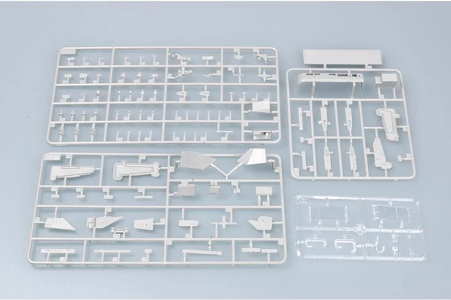 Three grey plastic model kit sprues and one clear plastic sprue for a 1/700 scale model ship on a light grey background.
