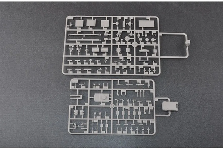 Two grey plastic model kit sprues containing various small ship parts laid out on a dark grey surface.
