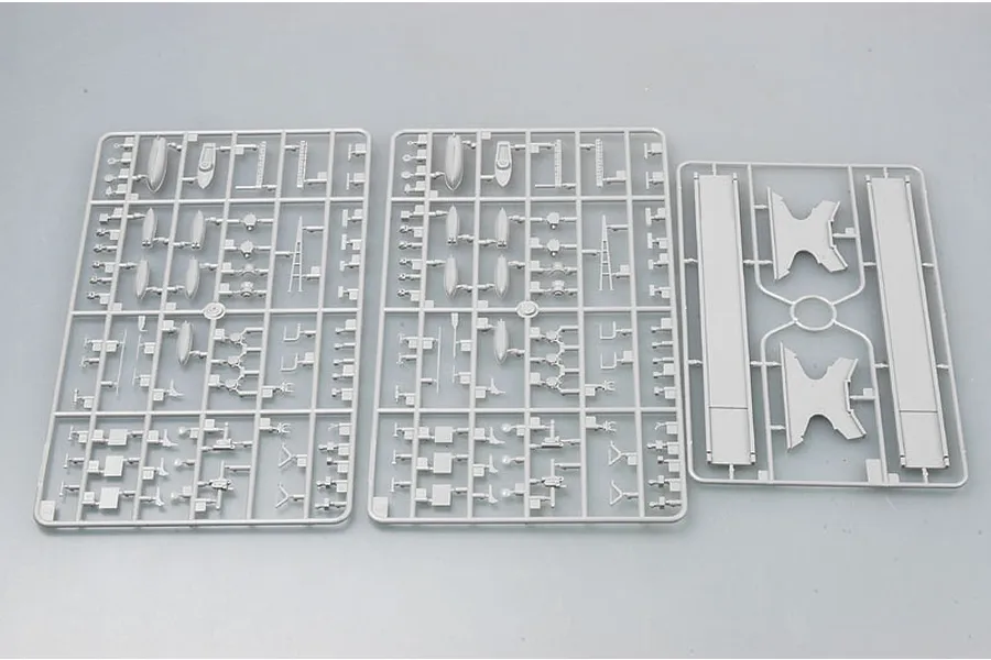 Three grey plastic model kit sprues containing various ship parts laid out on a plain surface.