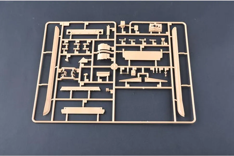 A tan plastic model kit sprue containing various tank parts on a dark grey background.