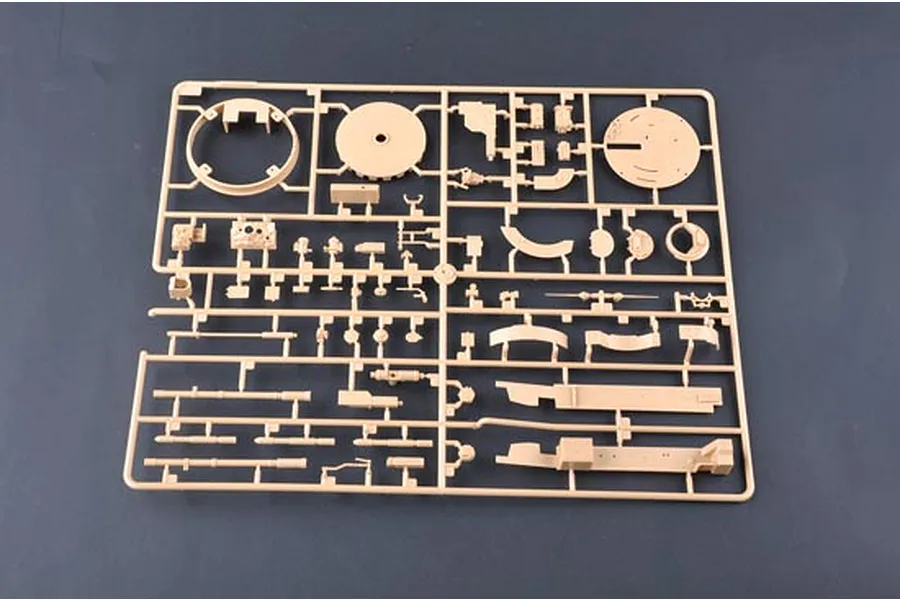 A tan plastic sprue containing various unattached parts for a 1/35 scale model tank kit, viewed from above on a dark grey background.