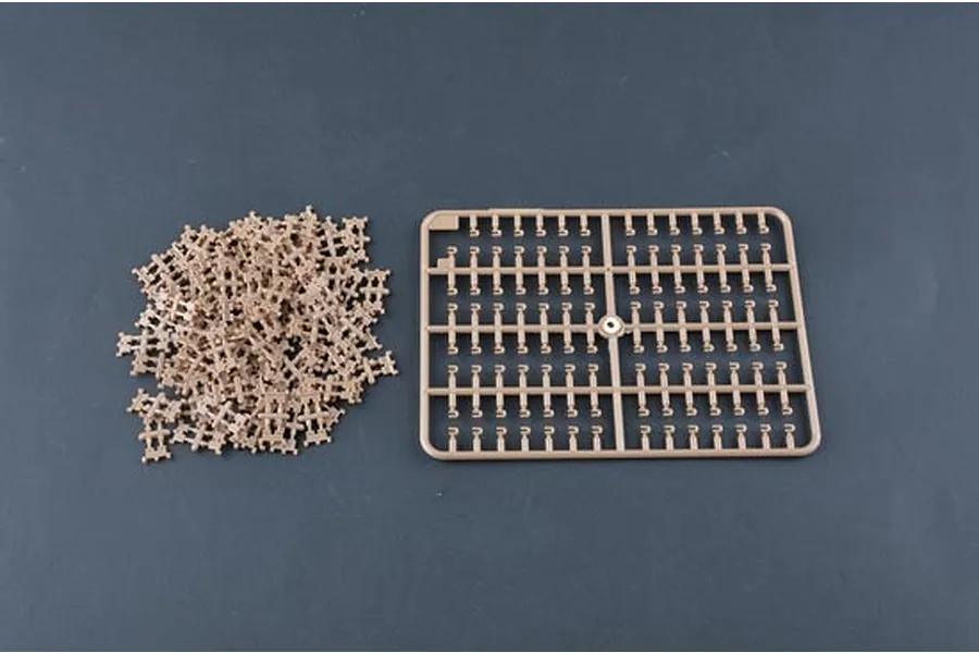 A pile of loose plastic tank track links and a single sprue frame containing more track links for a 1/35 scale model kit.