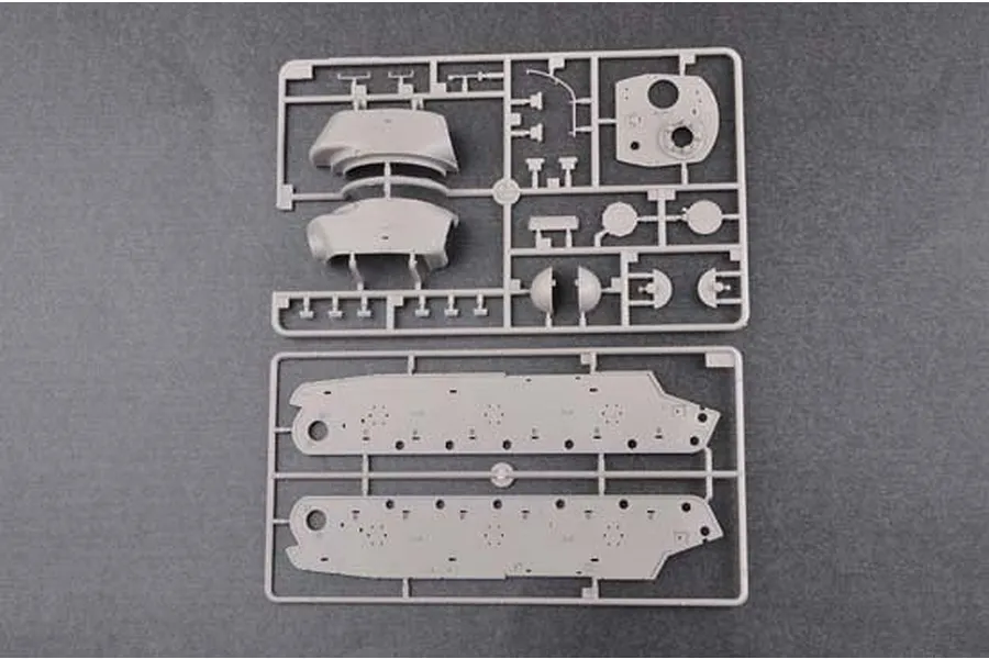 Two grey plastic model kit sprues containing tank hull and turret parts on a dark grey background.