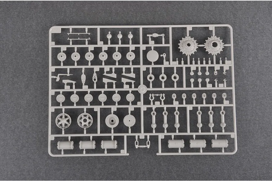 A grey plastic sprue containing various tank model parts, including road wheels, sprockets, and suspension components for a 1/35 scale model kit.