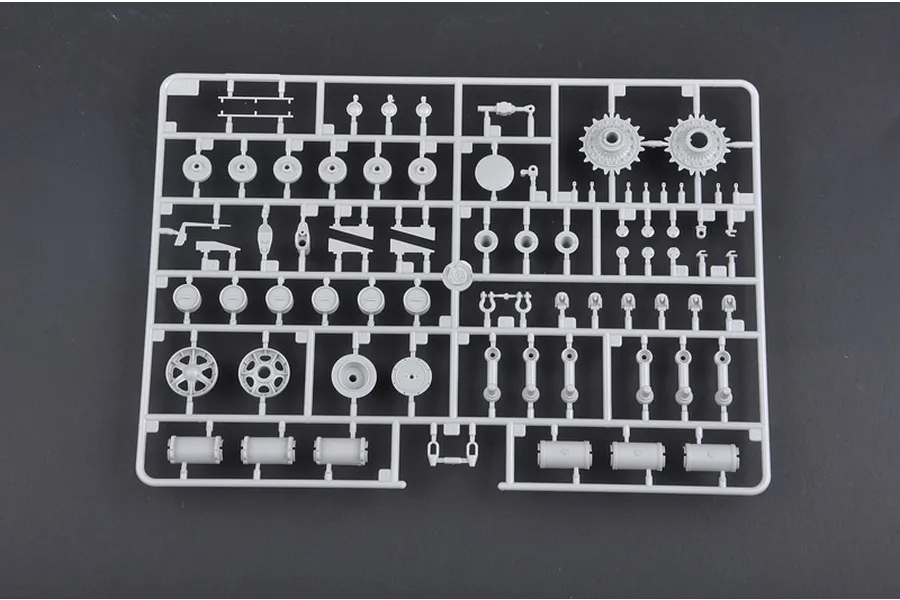 A grey plastic sprue containing various tank model parts, including wheels, sprockets, and suspension components for a 1/35 scale model kit.