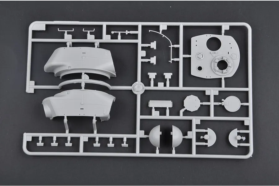A grey plastic sprue containing various tank model parts, including turret components and hull sections, for a 1/35 scale model kit.