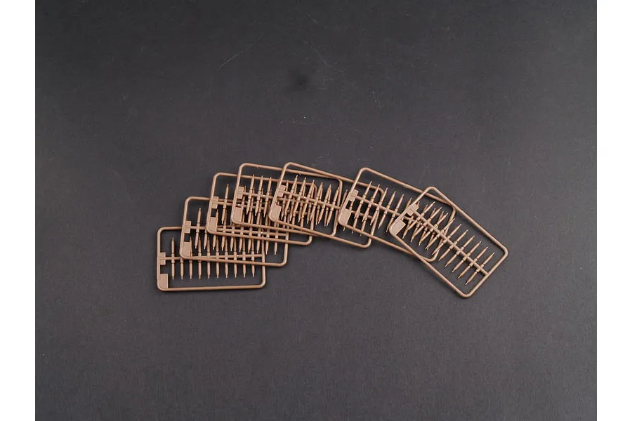 Five identical tan plastic model kit sprues containing small rod-like parts arranged in a fan shape on a dark grey background.