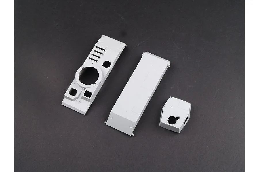 Unassembled grey plastic model tank parts including the upper hull, lower hull, and turret components on a dark background.