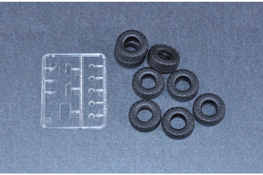 A set of seven black rubber tires and a small clear plastic sprue for a 1/35 scale model kit.
