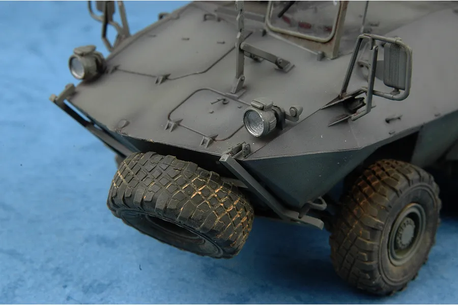 A close-up view of the front section of a 1/35 scale model of a Canadian Cougar AVGP armoured vehicle, showing the hull, headlights, and spare tire.
