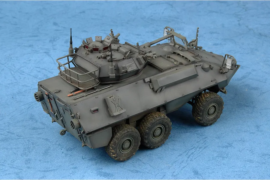 A 1/35 scale plastic model of a Canadian Cougar AVGP armoured vehicle, painted in olive drab and displayed on a blue textured background.