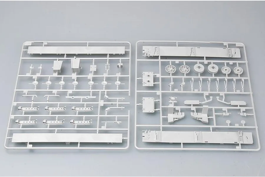 Two grey plastic model kit sprues containing various vehicle parts laid out on a plain surface.