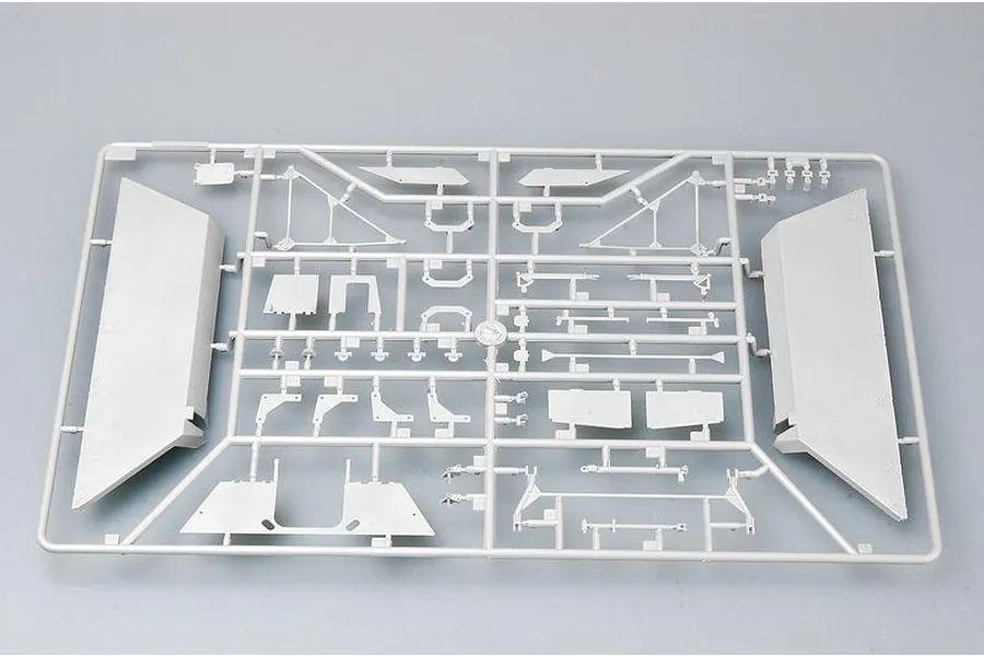 A grey plastic sprue containing various model kit parts for a 1/35 scale military vehicle, laid out on a plain grey surface.