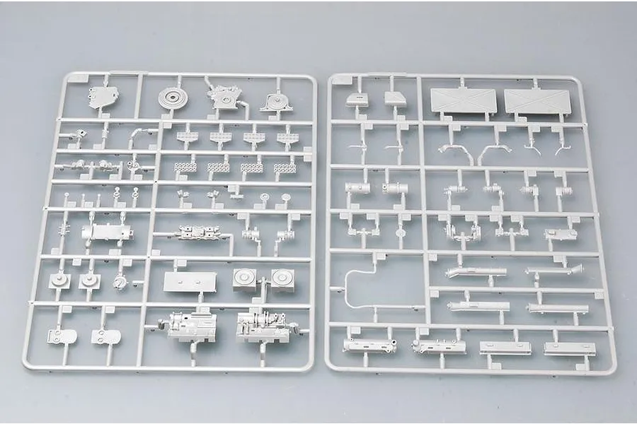 Two grey plastic model kit sprues containing various vehicle parts laid out on a plain grey surface.