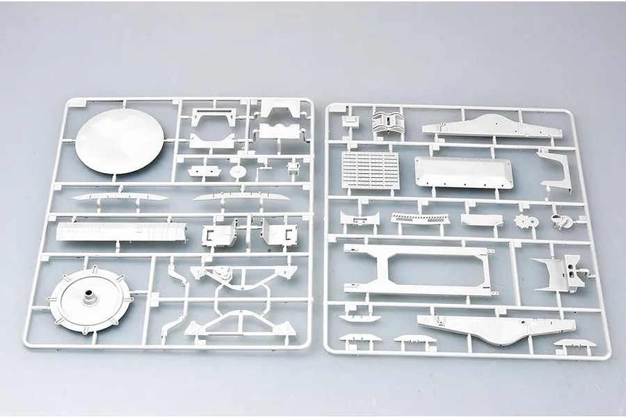 Two grey plastic model kit sprues containing various vehicle parts laid out on a plain surface.