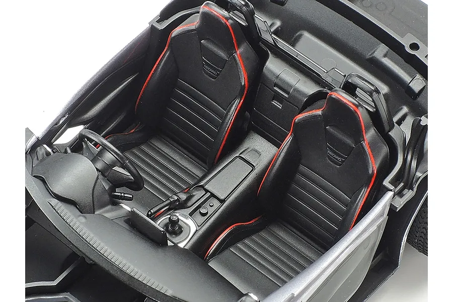Close-up of the detailed black interior of a 1/24 scale Tamiya Mazda Roadster RF model car, featuring Recaro bucket seats with red piping.