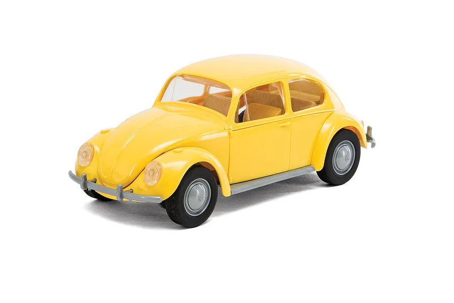 A yellow Airfix Quickbuild Volkswagen Beetle plastic model car viewed from a high angle against a white background.