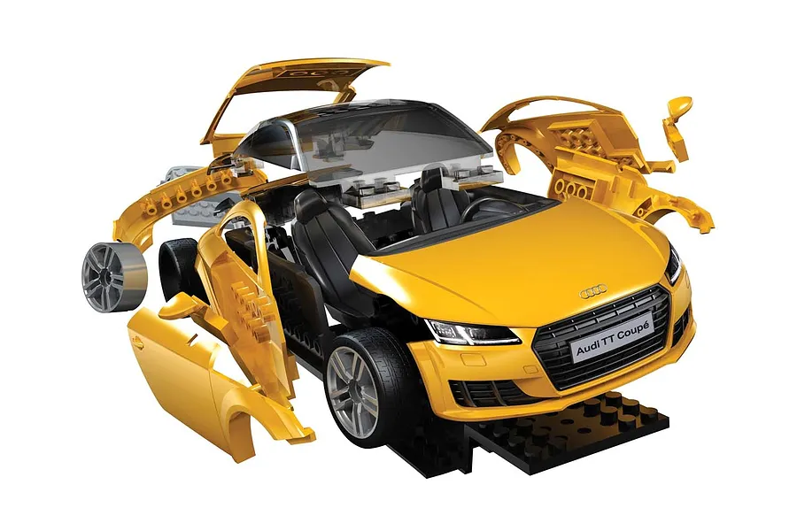 An exploded view of an Airfix Quickbuild Audi TT Coupe model kit in yellow, showing the car body panels and interior components separated.