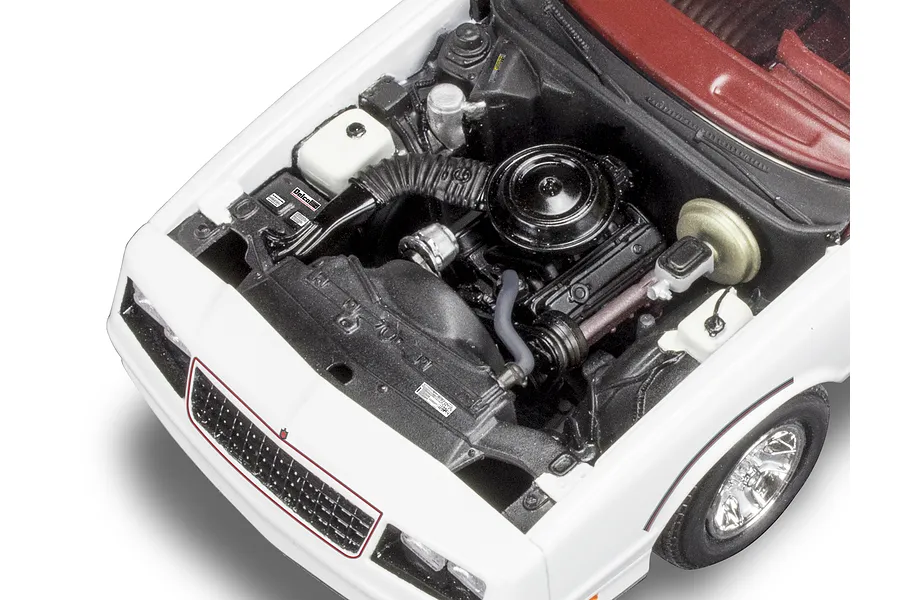 High-angle close-up of the detailed engine bay of a 1/24 scale Revell 1986 Monte Carlo SS model car, showing the engine, radiator, and interior dashboard.