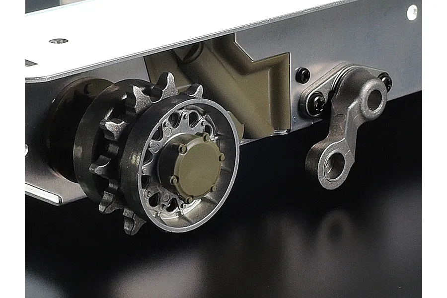Close-up of the drive sprocket and suspension arm assembly on a Tamiya 1/16 scale RC tank chassis.