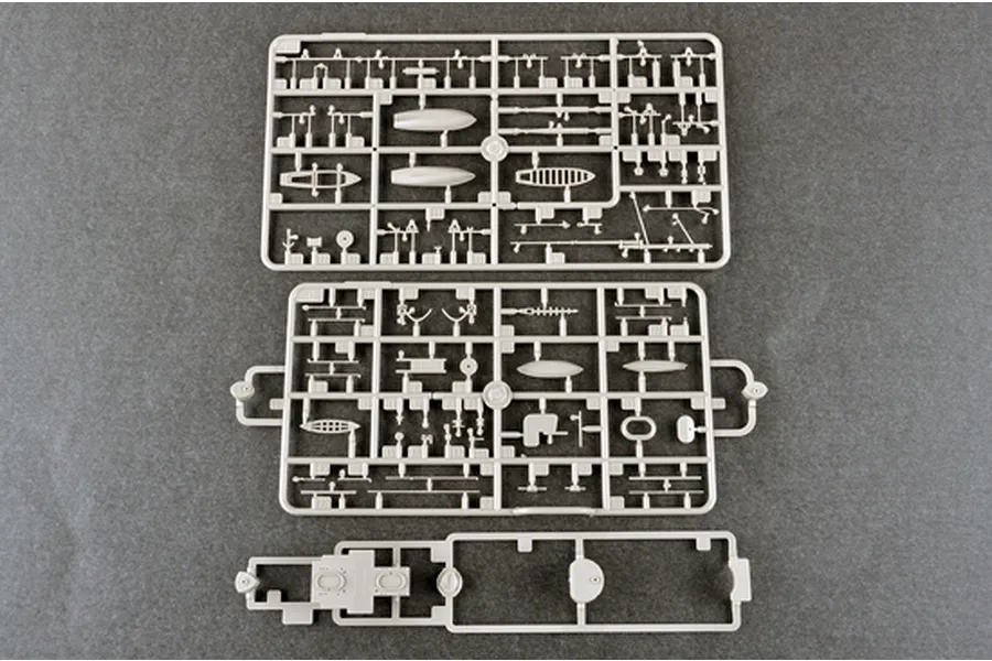 Three grey plastic model kit sprues containing various ship parts laid out on a dark grey surface.
