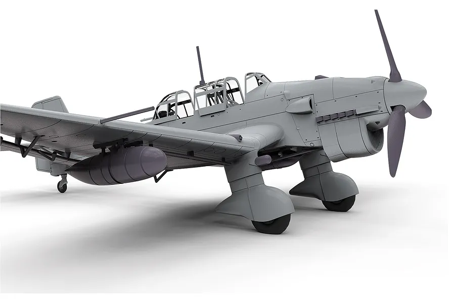 An unpainted grey plastic model kit of a Junkers Ju 87 Stuka dive bomber, shown from a low front-quarter angle against a white background.