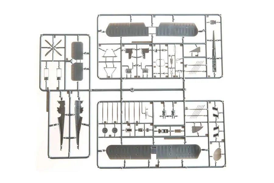 A top-down view of grey plastic model aircraft parts still attached to their sprues on a white background.