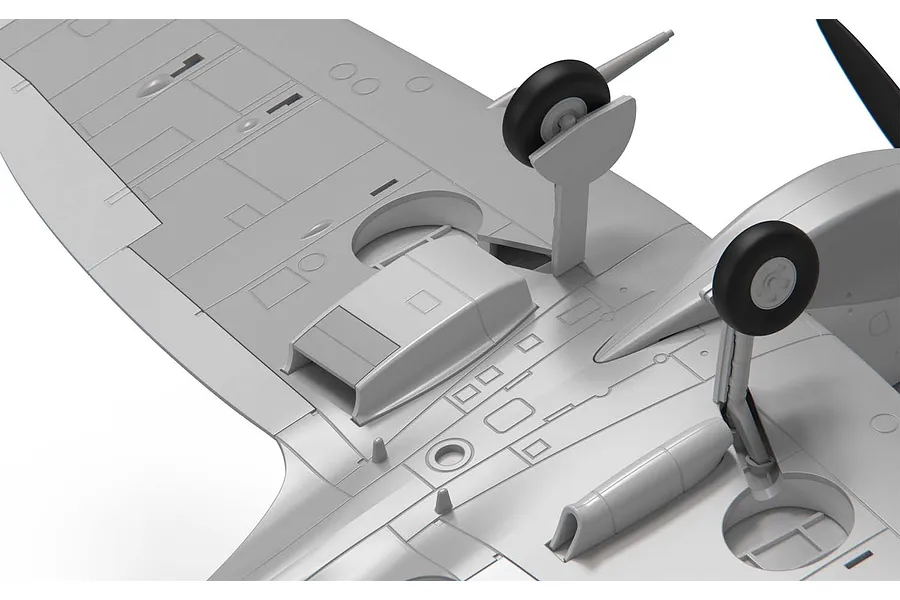 Close-up of the underside of an unpainted grey plastic model aircraft wing showing landing gear and panel details.