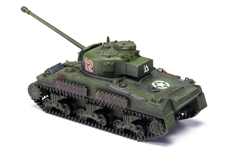 A 1/72 scale plastic model of a Sherman Firefly tank painted in olive green with weathering effects and decals.