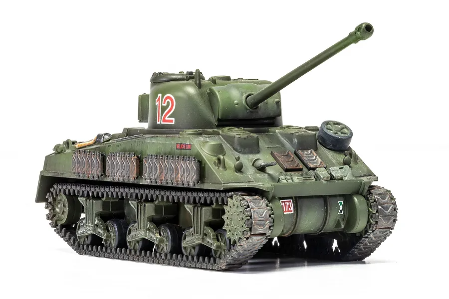 A 1/72 scale plastic model of a Sherman Firefly tank painted in olive green with the number 12 on the turret.