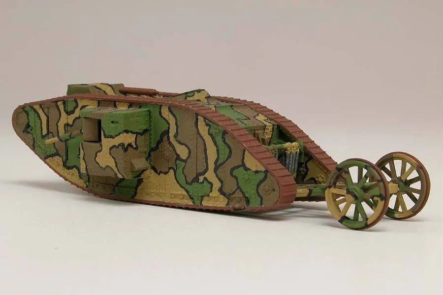 A painted 1/76 scale model of a WWI British Mark I Male tank with camouflage paint and a rear steering tail assembly.