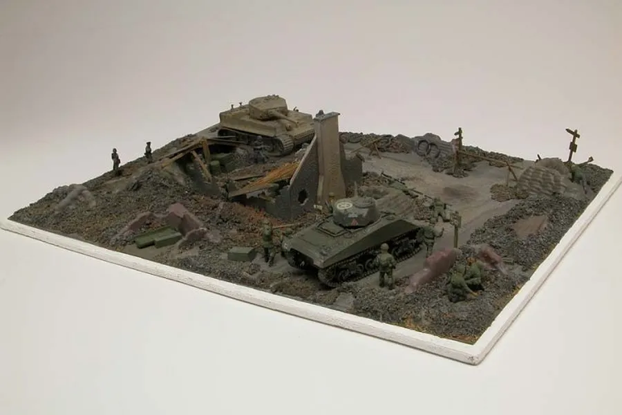 A completed 1/76 scale diorama featuring a battlefield scene with two tanks, ruined building walls, and several miniature soldier figures.