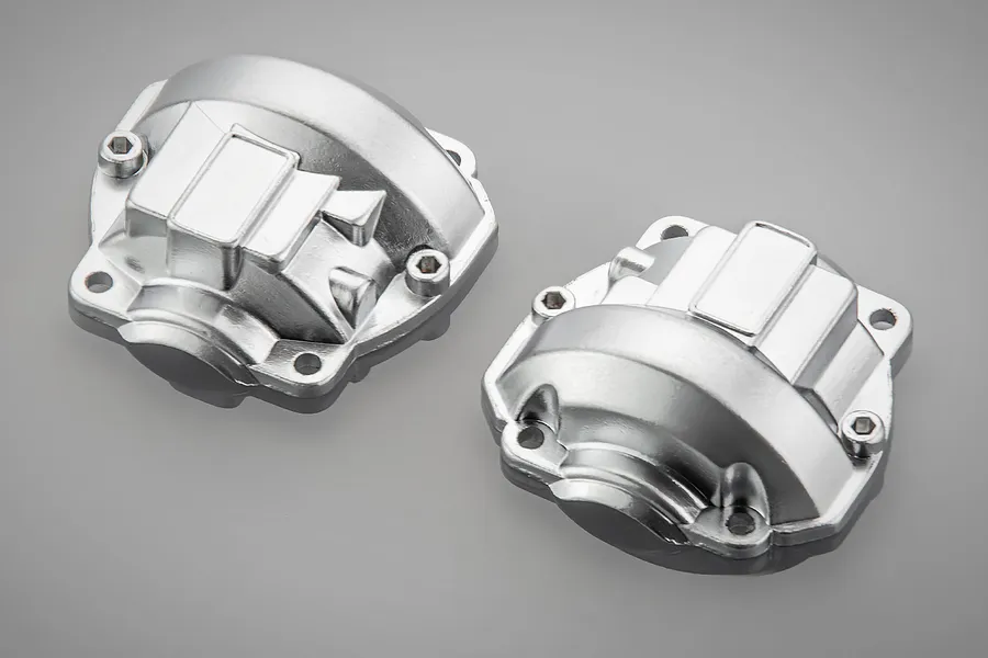 Two silver-coloured aluminium portal axle covers for an RC vehicle, shown from an angled perspective on a grey background.