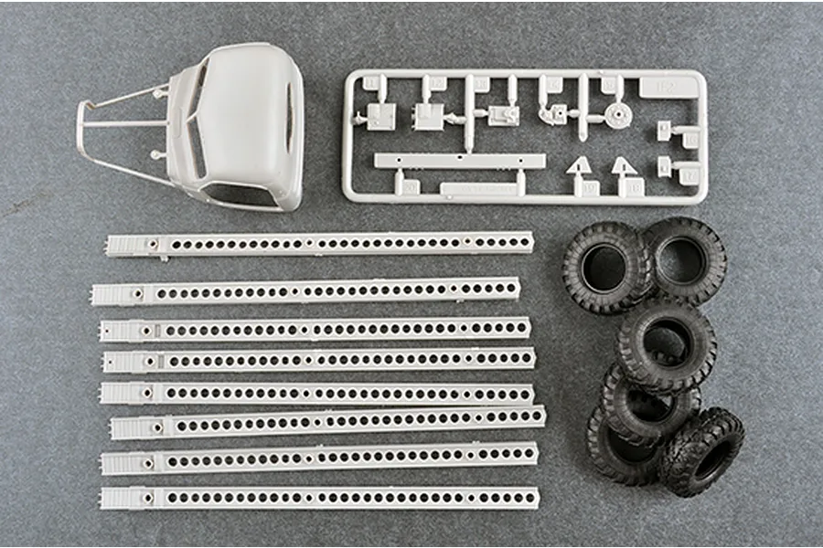 Plastic model kit parts for a 1/35 scale military vehicle, including a truck cab, rocket launcher rails, and rubber tires.