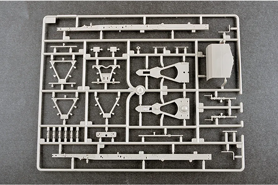 A grey plastic sprue containing various model kit parts for a 1/35 scale military vehicle, including chassis rails and suspension components.