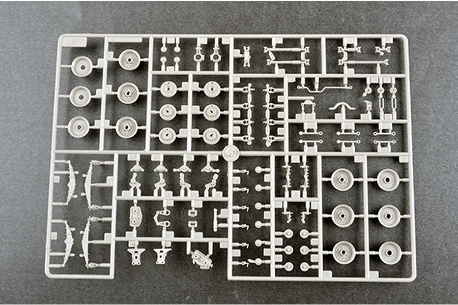 A grey plastic model kit sprue labeled E, containing various small parts for a 1/35 scale military vehicle model, including wheels and suspension components.
