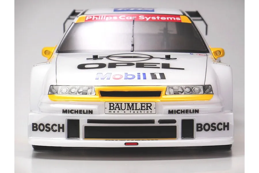 Front view of a Tamiya Opel Calibra V6 RC touring car body shell featuring white, yellow, and black racing livery with sponsor decals.