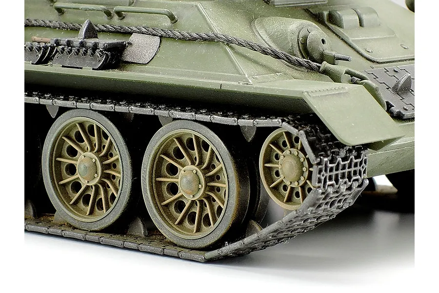 Close-up of the tracks and wheels of a Tamiya 1/48 scale Russian T-34/85 tank model, showing olive green paint and detailed road wheels.