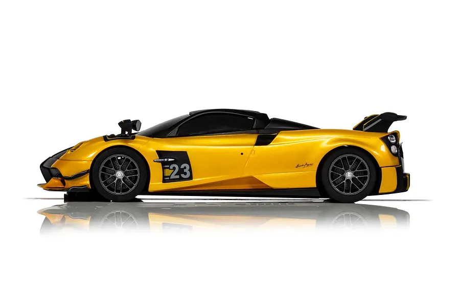 Side profile of a yellow Scalextric 1/32 scale Pagani Huayra BC Roadster slot car with black accents and number 23 on the door.
