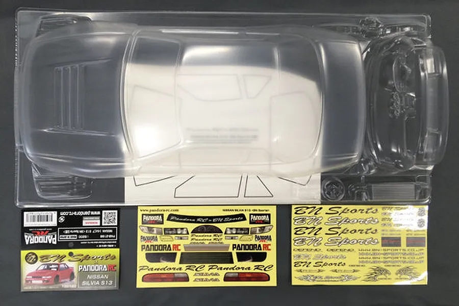 Unpainted clear polycarbonate RC car body shell for a Nissan Silvia S13 by Pandora RC, including decal sheets and packaging.
