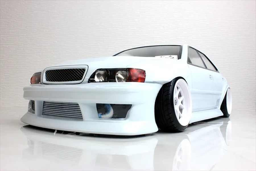 A low-angle studio shot of a white 1/10 scale Toyota Chaser JZX100 RC drift car body shell with BN Sports styling, featuring white wheels and a front intercooler.