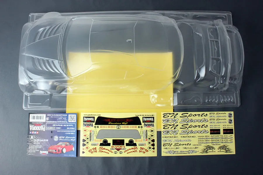 Unpainted clear polycarbonate RC car body shell for a Toyota 86 ZN6 with BN-Sports styling, including decal sheets and packaging header card.