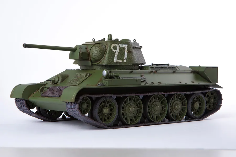 A fully assembled and painted 1/35 scale plastic model of a Soviet T-34/76 tank, featuring olive green paint and the number 27 on the turret.