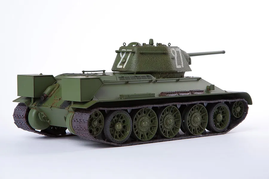 A 1/35 scale plastic model of a Soviet T-34/76 tank, painted in olive green with white turret markings, viewed from the rear three-quarter angle.
