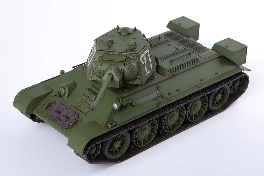 A high-angle studio shot of an assembled and painted 1/35 scale Academy T-34/76 tank model, featuring olive green paint and white turret markings.